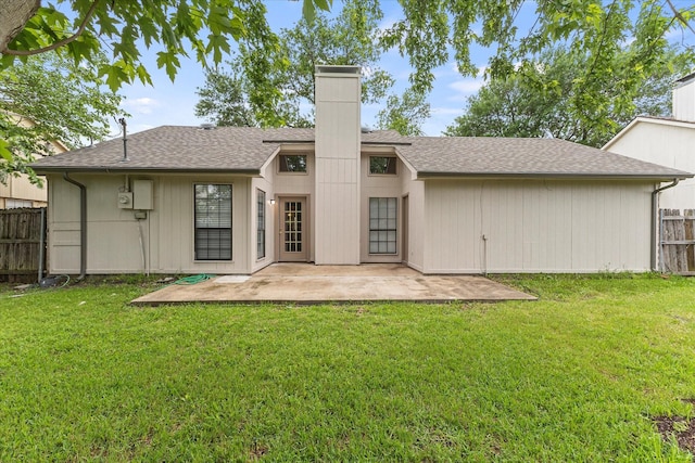 back of property featuring fence, a patio, a chimney, and a yard