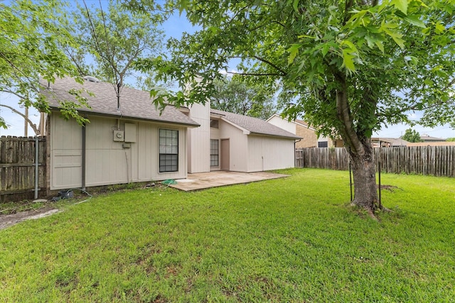 rear view of property featuring a lawn, a patio, a shingled roof, and a fenced backyard