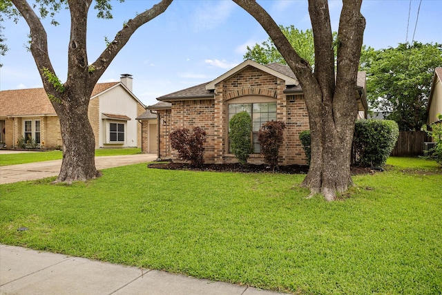 single story home with roof with shingles, an attached garage, brick siding, a front yard, and driveway