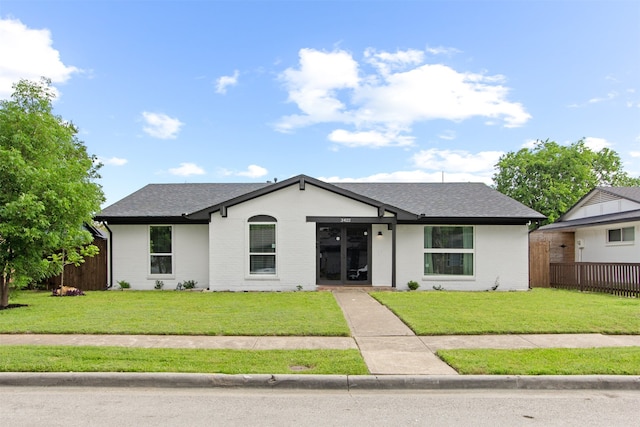 view of front of house featuring fence, roof with shingles, and a front yard