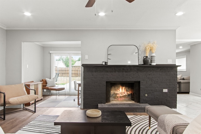 living room with plenty of natural light, ornamental molding, a brick fireplace, and a ceiling fan