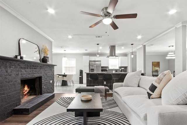 living room featuring crown molding, ceiling fan, wood finished floors, and visible vents