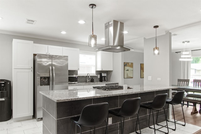 kitchen with appliances with stainless steel finishes, a kitchen breakfast bar, white cabinetry, island range hood, and visible vents