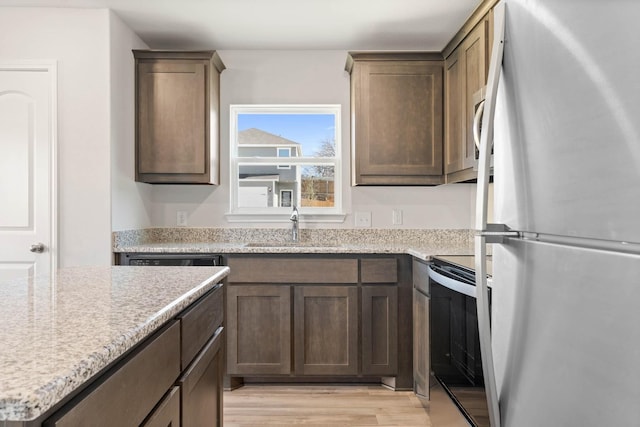 kitchen featuring freestanding refrigerator, dark brown cabinets, a sink, light wood-style flooring, and stainless steel range with electric cooktop