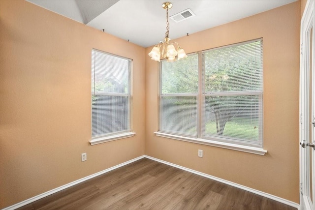 unfurnished dining area featuring a chandelier, baseboards, and wood finished floors