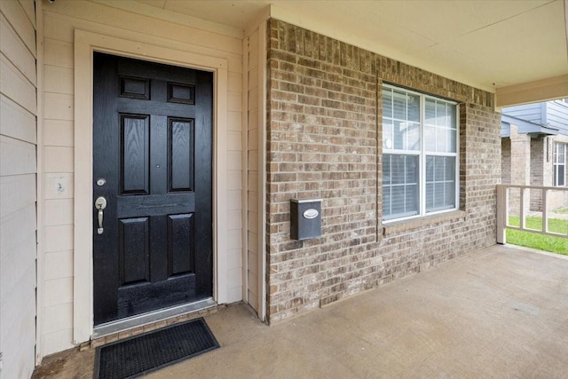 entrance to property with brick siding and covered porch