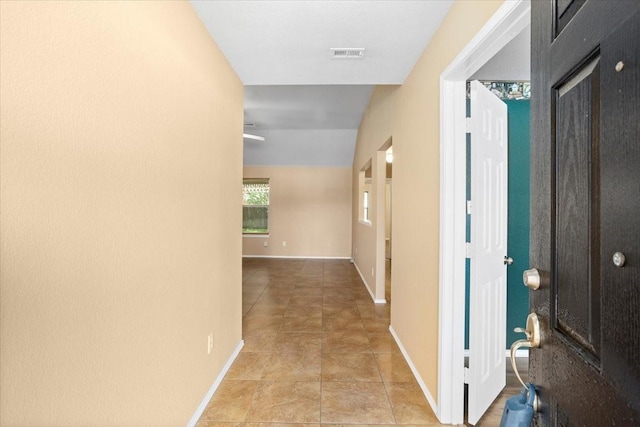 hallway with light tile patterned floors and baseboards