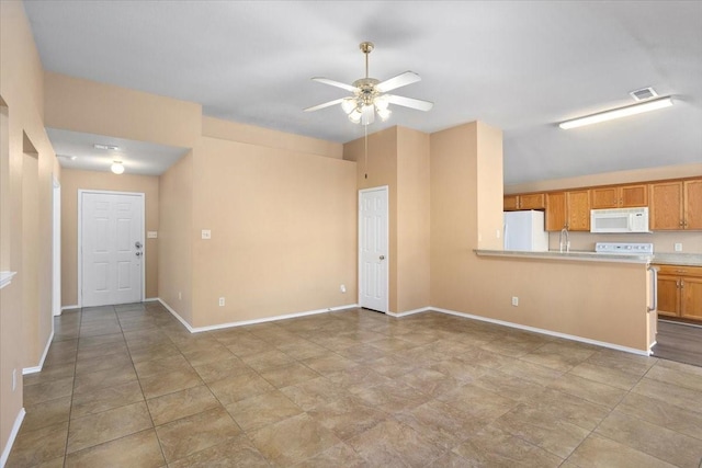 unfurnished living room featuring a ceiling fan, baseboards, and a sink