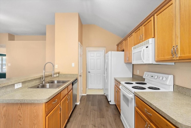 kitchen featuring white appliances, a sink, dark wood finished floors, brown cabinetry, and a peninsula