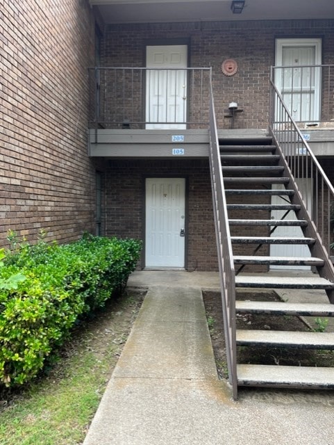 view of exterior entry with a balcony and brick siding