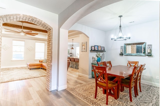 dining room with visible vents, arched walkways, wood finished floors, baseboards, and ceiling fan with notable chandelier