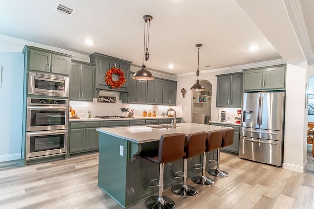 kitchen with appliances with stainless steel finishes, ornamental molding, light wood-type flooring, and visible vents