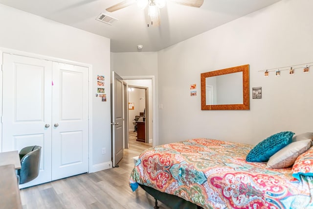 bedroom with light wood-style floors, ceiling fan, visible vents, and a closet
