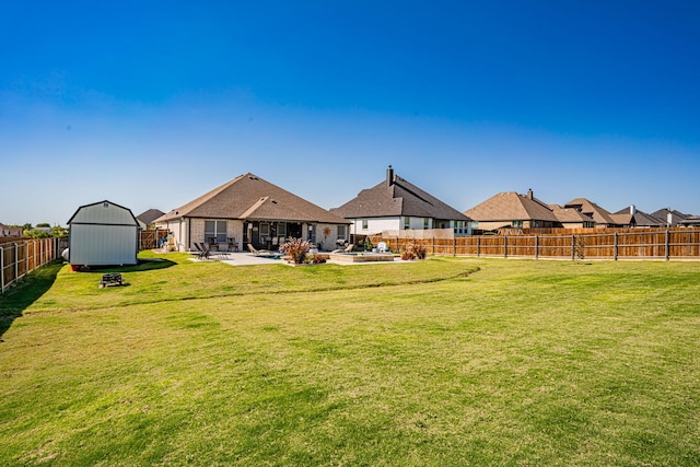 rear view of property with a shed, a fenced backyard, an outbuilding, a patio area, and a yard