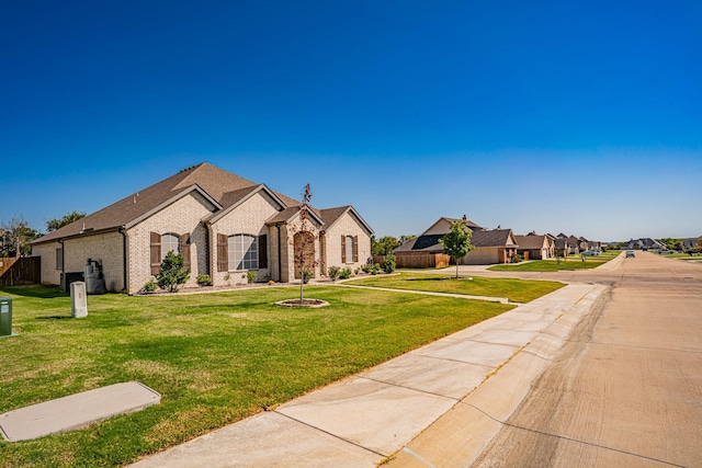french country home featuring brick siding, fence, and a front yard