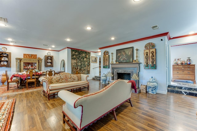 living room with crown molding, visible vents, wood finished floors, recessed lighting, and a premium fireplace