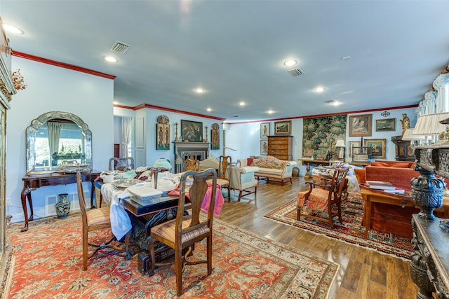 dining space featuring crown molding, a fireplace, recessed lighting, and wood finished floors