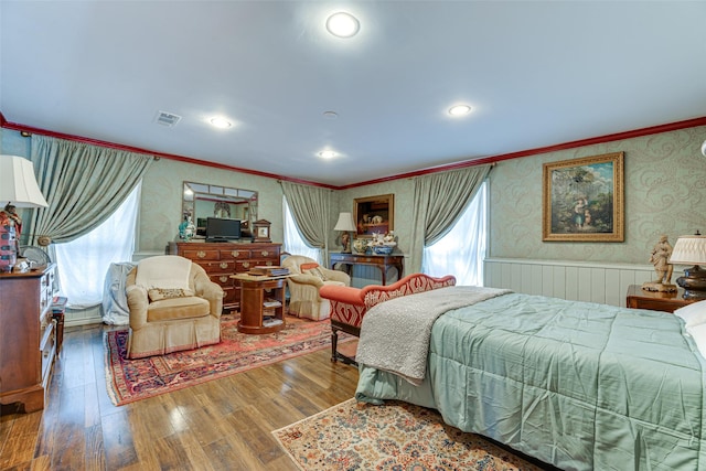 bedroom with a wainscoted wall, ornamental molding, wallpapered walls, and wood finished floors