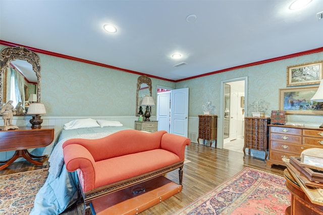 bedroom featuring visible vents, wood finished floors, and a wainscoted wall