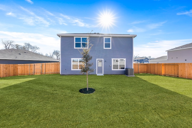 rear view of property featuring a lawn, central AC unit, and a fenced backyard