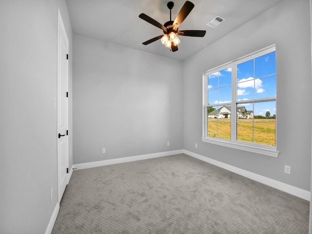 carpeted empty room with baseboards, a ceiling fan, and visible vents