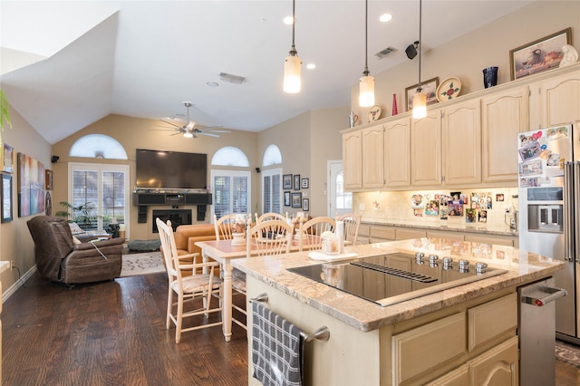 kitchen with black electric cooktop, visible vents, dark wood-style floors, and stainless steel fridge with ice dispenser