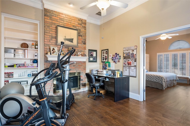 office space featuring a brick fireplace, a ceiling fan, crown molding, and wood finished floors