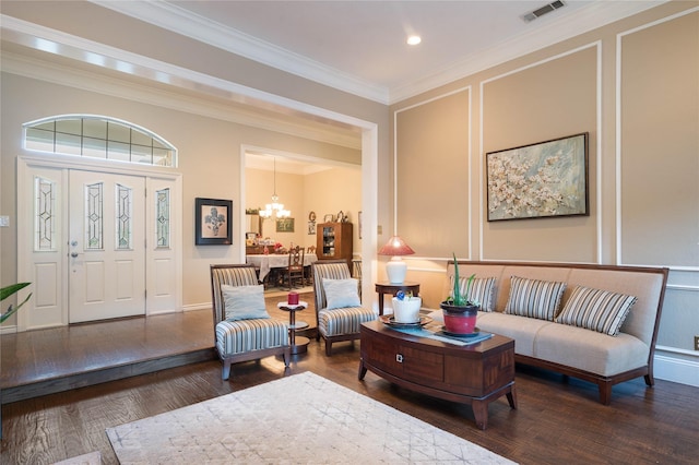 sitting room featuring visible vents, crown molding, wood finished floors, a decorative wall, and a chandelier
