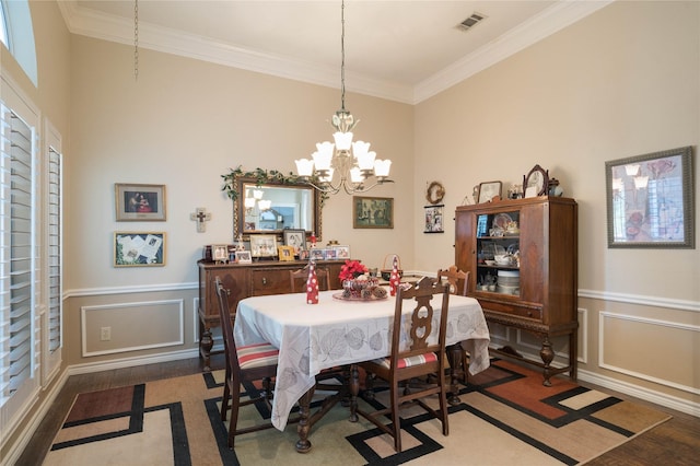dining room featuring visible vents, crown molding, wood finished floors, a wainscoted wall, and an inviting chandelier