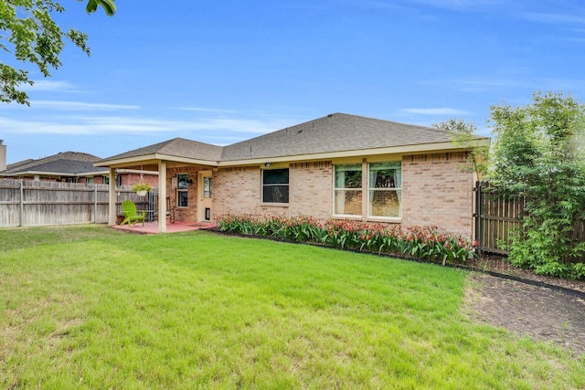 back of property featuring roof with shingles, brick siding, a fenced backyard, a lawn, and a patio