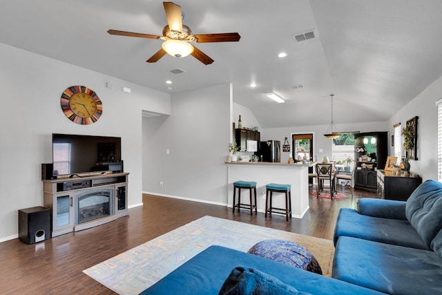 living room with ceiling fan, vaulted ceiling, dark wood finished floors, and visible vents