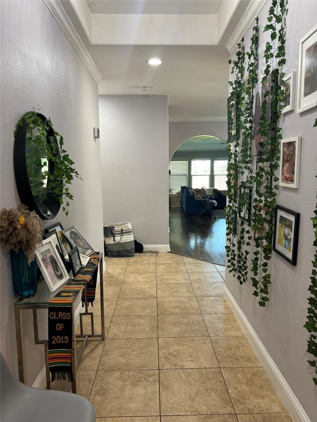 hall featuring crown molding, arched walkways, tile patterned floors, and recessed lighting