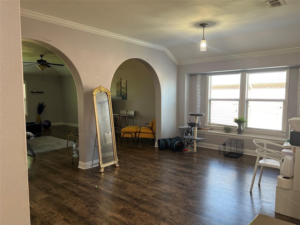 interior space featuring ceiling fan, arched walkways, baseboards, wood finished floors, and ornamental molding