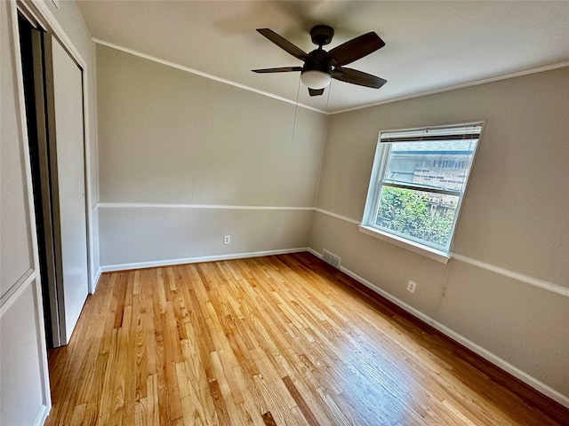 empty room featuring visible vents, ornamental molding, light wood-style floors, baseboards, and ceiling fan