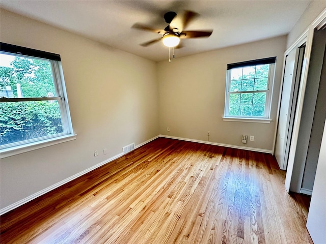 unfurnished bedroom featuring baseboards, ceiling fan, wood finished floors, and visible vents