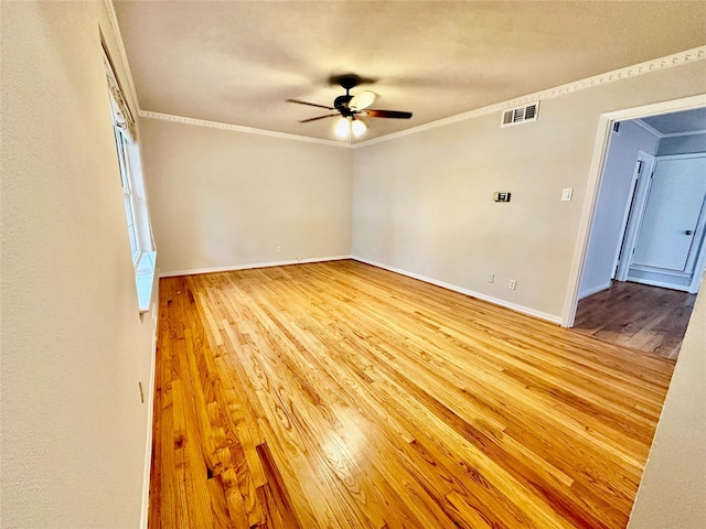 empty room with ornamental molding, a ceiling fan, wood finished floors, and visible vents