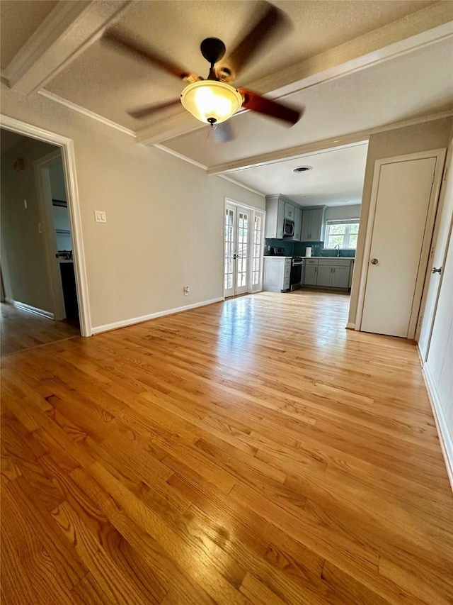 unfurnished living room featuring light wood-style floors, baseboards, a ceiling fan, and beam ceiling