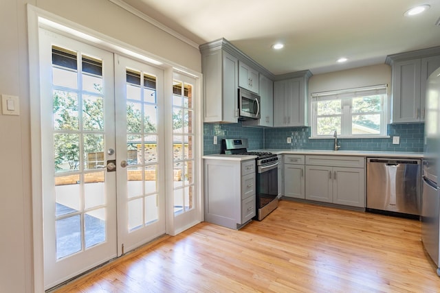 10816 Palace Way, Dallas, TX 75218 - kitchen featuring appliances with stainless steel finishes, gray cabinetry, backsplash, light wood-type flooring, and recessed lighting