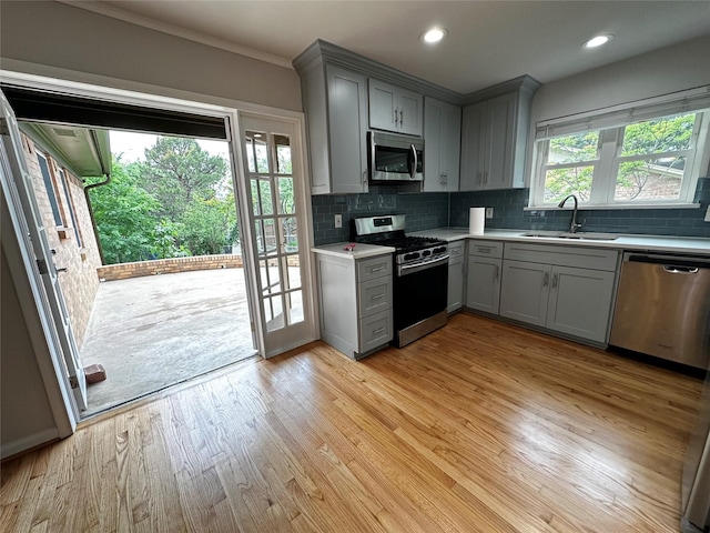 kitchen featuring gray cabinets, backsplash, appliances with stainless steel finishes, a sink, and light countertops