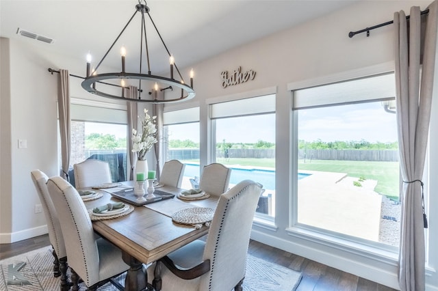 dining room with a chandelier, baseboards, visible vents, and wood finished floors