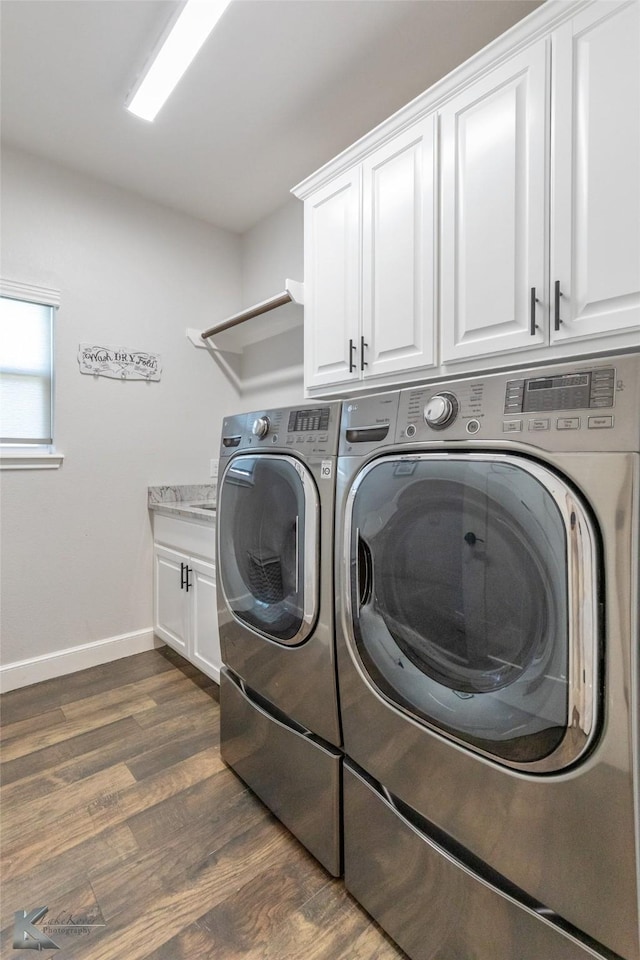washroom with cabinet space, independent washer and dryer, baseboards, and dark wood-type flooring