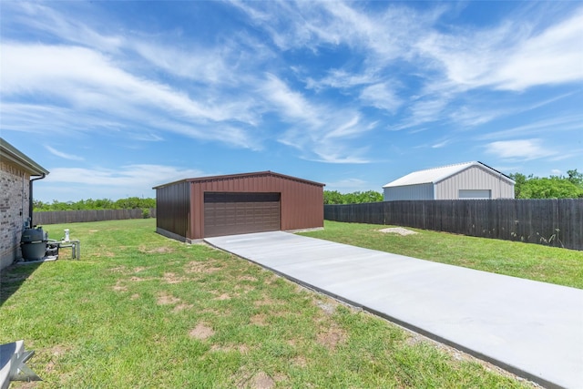 view of yard featuring an outdoor structure, a fenced backyard, and a detached garage