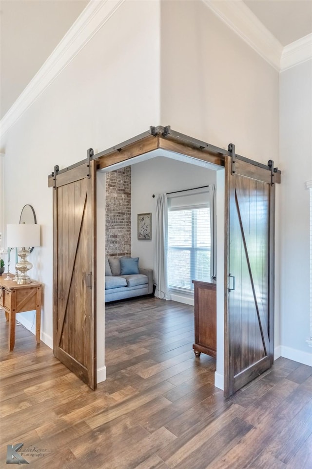 additional living space featuring baseboards, a barn door, and wood finished floors