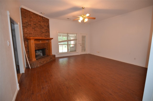 unfurnished living room with crown molding, a brick fireplace, wood finished floors, baseboards, and a ceiling fan