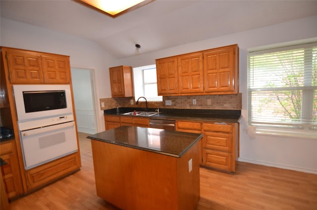 kitchen featuring black microwave, white oven, a sink, dishwasher, and vaulted ceiling