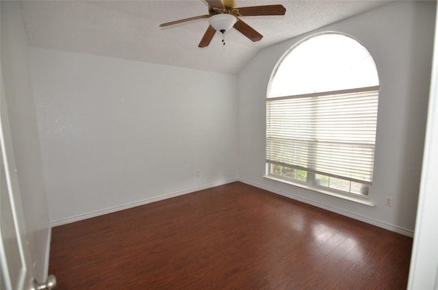 empty room with a ceiling fan, baseboards, vaulted ceiling, and dark wood-style floors