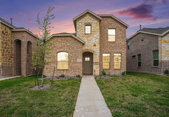 view of front facade with a yard and brick siding
