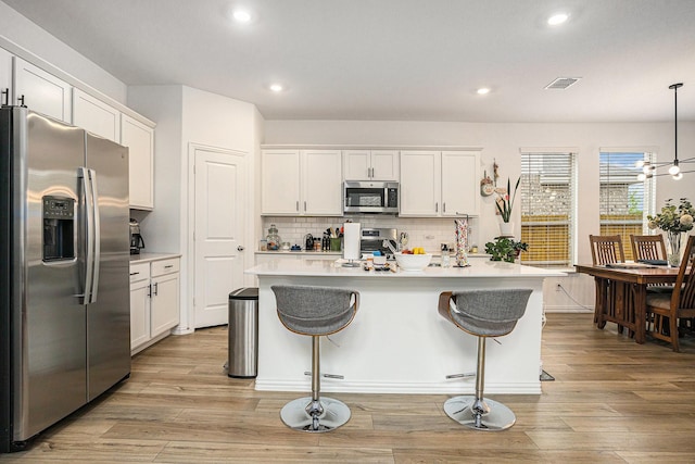 kitchen with visible vents, light countertops, white cabinets, light wood-style floors, and stainless steel appliances