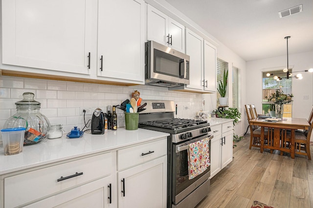 kitchen with stainless steel appliances, visible vents, white cabinetry, and light wood-style floors