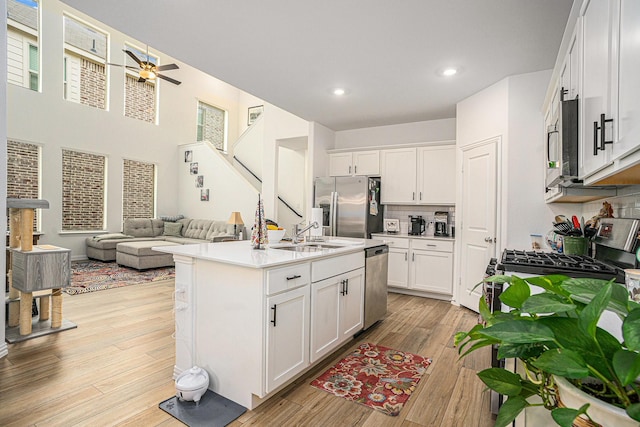 kitchen with a sink, a ceiling fan, white cabinets, and stainless steel appliances